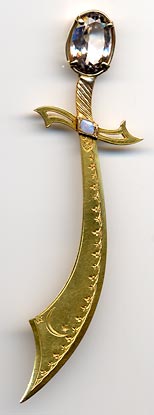This bookmark was made in the US. It is 14K gold with a lead crystal on top and an opal underneath. It is marked 14K R. Schaezlein. The top blade is finely scribed with an intricate design having a crescent moon and a star. 