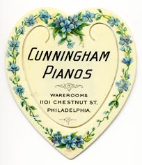 This bookmark was made in the US by Meek Company of Coshocton, D. It is a celluloid advertising bookmark for Cunningham pianos. It is in the shape of a heart with blue flowers along the outside edge. On the back is a picture of an upright piano with the words, 'Buy the Matchless Cunningham Piano. We offer $10,000 for a better piano.'" The date is 1900 - 1915."