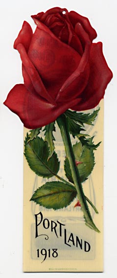 This bookmark was made in the US by the Whitehead and Hoag Co. of Newark, NJ. It is a celluloid travel advertising bookmark for Portland, Oregon. The flower on top is a rose and it has a tiny hole where a tassel once was. The back has a photo of Mt. Hood and another of a car traveling on a highway. It says, "Portland Ad. Club. Meet me on the Columbia River Highway Portland 1918." The copyright is dated 1915.