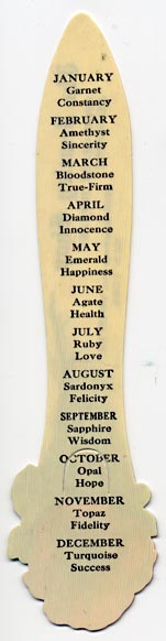  This bookmark was made in the US for The Jewelry Shop in New York. It is a celluloid advertising bookmark with a red flower on top. The back is a list of every month and the birth stone and a word for the month. The date is 1900 - 1910.