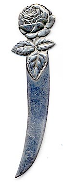 This bookmark was manufactured in the US by Towle Silversmiths. It is marked with the familiar hallmark of the T enclosing a lion along with Sterling and the number 17. This is a very interesting piece because the front is a very detailed relief of a rose and the back has a scored picture of an angel. The date is 1890 - 1920.