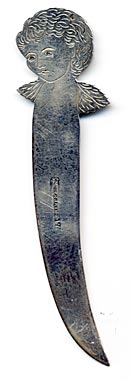 This bookmark was manufactured in the US by Towle Silversmiths. It is marked with the familiar hallmark of the T enclosing a lion along with Sterling and the number 17. This is a very interesting piece because the front is a very detailed relief of a rose and the back has a scored picture of an angel. The date is 1890 - 1920.