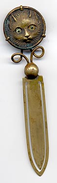  This bookmark was made in France. It is brass and the top is a relief picture of a kitty with light green glass eyes. The date is 1890 - 1910.  