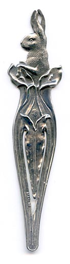 This bookmark was made in the US by an unknown manufacturer. It is marked sterling on the lower outer blade. The top is a rabbit poking his body out of a lily flower. This was most likely an Easter gift. It was sold in the 1910 Shreve catalog. 