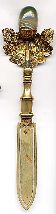 This bookmark was made in England or Scotland and is made of brass. The top is a pair of leaves with a green and white banded agate thistle. The date is 1900 - 1910.