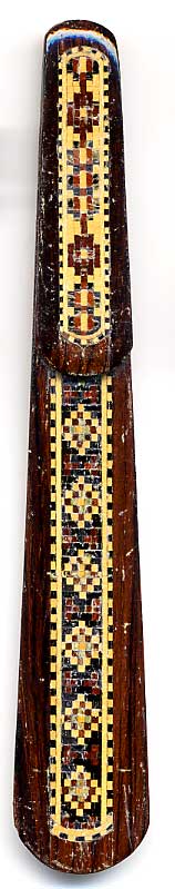 This bookmark was made in England. It is a piece of Tunbridge Ware. "Tunbridge ware is a form of decoratively inlaid woodwork characteristic of the spa town of Tunbridge Wells in Kent in the 18th and 19th centuries. The decoration typically comprises a mosaic of many very small pieces of different coloured woods that form a pictorial vignette. Shaped rods and slivers of wood were first carefully glued together, then cut into many thin slices of identical pictorial veneer with a fine saw. Elaborately striped and feathered bandings for framing were pre-formed in a similar fashion." The date is 1880 - 1900.