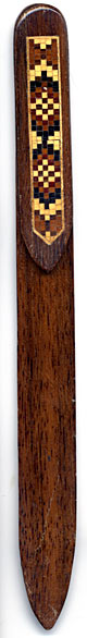 This bookmark was made in England. It is a piece of Tunbridge Ware. "Tunbridge ware is a form of decoratively inlaid woodwork characteristic of the spa town of Tunbridge Wells in Kent in the 18th and 19th centuries. The decoration typically comprises a mosaic of many very small pieces of different coloured woods that form a pictorial vignette. Shaped rods and slivers of wood were first carefully glued together, then cut into many thin slices of identical pictorial veneer with a fine saw. Elaborately striped and feathered bandings for framing were pre-formed in a similar fashion." The date is 1880 - 1900.