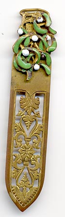 This bookmark was made in France by an unknown manufacturer. It is gold doré and green and white enamel. The blade has an intricate cutout design.
