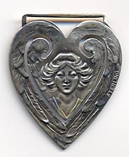 This bookmark was made in the US by Webster Co. It is only marked sterling. It is in the shape of a heart with a picture of a woman in the center. The date is 1913. 