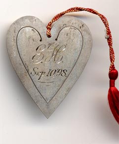 This bookmark was made in the US by an unknown manufacturer. It is in the shape of a heart with an inscribed design on the inner blade. The back is marked sterling and has the inscription "E.H. Sep. 10 '98". A red tassel is attached at the top.