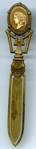 This bookmark was made in France. It is unmarked gilded brass and has a cameo on top. The date is 1890 - 1910.