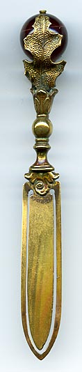 This brass bookmark was made in Europe and is in the shape of a thistle with an agate marble between the leaves.