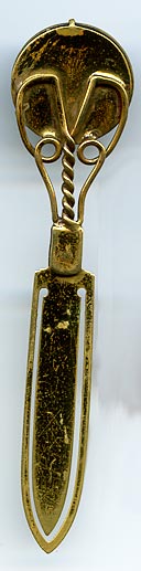 This brass bookmark has a medallion with a Billiken in the center. According to Wikipedia, the Billiken was a charm doll created by an American art teacher and illustrator, Ms. Florence Pretz of Kansas City, Missouri, who is said to have seen the mysterious figure in a dream. In 1908 she patented the Billiken who was elf-like with pointed ears, a mischievous smile, and a tuft a hair on his pointed head. His arms were short and he was generally sitting with his legs stretched out in front of him.
