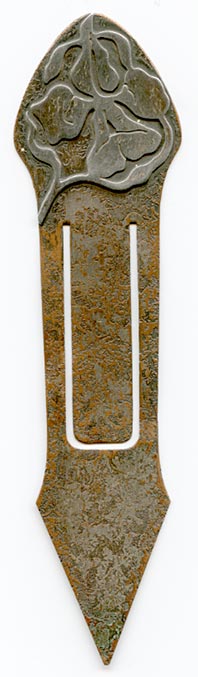 This bookmark was made in the US by the Heintz Art Metal Shop. It is unmarked. The top is sterling overlay of a flower. The bookmark is bronze with a florentine brown finish. The date is 1910 - 1920.