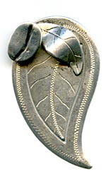 This bookmark was made in El Salvador. It is marked 900 and El Salvador. It is in the shape of a coffee leaf with a coffee bean and another leaf on top.