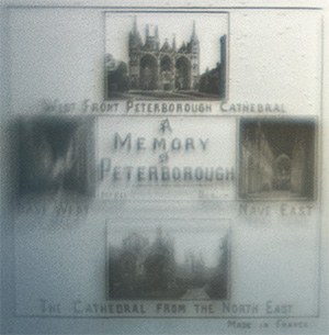 This bookmark is made in France and is a Stanhope or 'peeper'" bookmark. It is probably silver plate over brass on the fleur de lis on top and brass blades. It was made between 1890 and 1920. If you look through the '"peep hole'" you can see 4 photographs of different scenes with '"A Memory of Peterborough'" in the center. The scenes are: (counter clockwise from the top) '"West Front Peterborough Cathedral'", '"Nave West'", Nave East'", and The Cathedral form the North East'". It also says Made in France."
