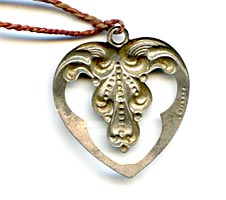 This bookmark was made in the US by an unknown manufacturer. It is a tiny repousse heart shape with a red string tassel and is marked sterling.