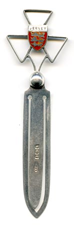 This bookmark, a 'Jersey' souvenir, was made in Birmingham England in 1925 by E Horton & Co. It is a George V English sterling silver bookmark with an enamel coat of arms on a three point cross above a ball.