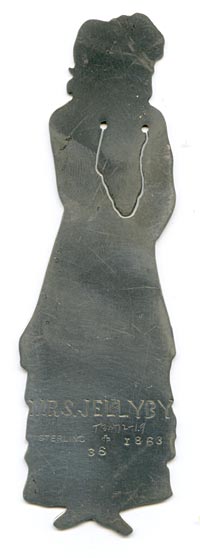 This bookmark was made in the US by J.F. Fradley. It is marked on the back with sterling, the manufacturers hallmark of a cross, the numbers 1863 and 36, and Mrs. Jellyby. This is a figure of the Dickens character from the book "Bleak House." The date is 1890 - 1936.