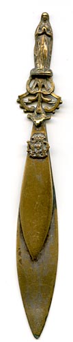 This bookmark was made in France as a souvenir for Our Lady of Lourdes, depicted as the finial on the top. It is brass with warn silver plating. The Lourdes shield is highlighted above.