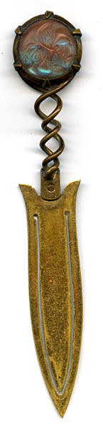 This bookmark was made in Europe, possibly France. The top is a medallion made of saphiret glass in the shape of a moon face caricature. It is a brass bookmark with a dorè finish. The date is 1870 - 1900. 