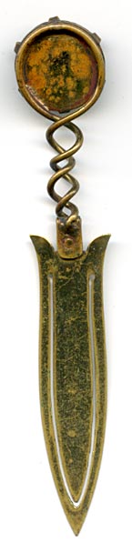 This bookmark was made in Europe, possibly France. The top is a medallion made of saphiret glass in the shape of a moon face caricature. It is a brass bookmark with a dorè finish. The date is 1870 - 1900. 