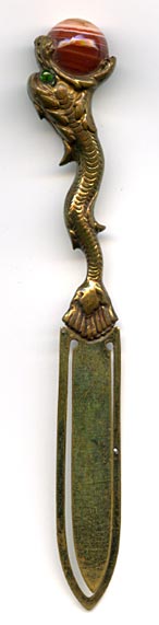This brass bookmark was made in France by an unknown manufacturer. It is a sea dragon with a banded agate marble in it's mouth. It has green glass eyes and is highly detailed.