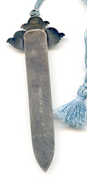 This bookmark was made in the US by an unknown manufacturer. The top has three cherub faces it high relief and has a 10.5 inch tassel. 