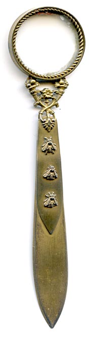 This bookmark was made in France. The top is a magnifying glass held up by two horns of fruit. The top blade has 3 bees (a symbol of Napoleon). It has two French hallmarks on the side of the glass. 