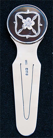 This bookmark was made in London, England. It is hallmarked for 1913 London by C. Bros. The top is tortoise shell inlaid with a silver flower design.