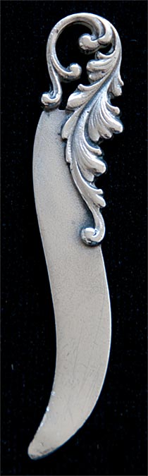 This bookmark was made in the US by Gorham. It is a small bookmark or letter opener with one blade. The top has a floral design.