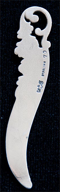 This bookmark was made in the US by Gorham. It is a small bookmark or letter opener with one blade. The top has a floral design.