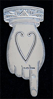 This bookmark was made in Birmingham, England by Chrisford and Norris. it is hallmarked for Birmingham 1905. The bookmark is in the shape of a hand with the index finger pointing down.
