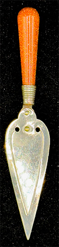 This bookmark was made in the US. It is a masonic piece in the shape of a trowel with a goldstone handle. The date is sometime in the 1950s when goldstone was very popular.
