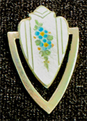 This bookmark was made in the US by F. A. Herman. It is marked with a hallmark of a triangle enclosing the letter H and sterling. The top is a white enamel shield with flowers. The date is 1900 - 1910.