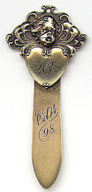 This bookmark was manufactured in the US by Gorham. It is finished in a gold plate or wash over sterling. It has a cherub and a heart on the top and the blade is inscribed Oct 14 '98. It is marked with the Gorham hallmark, Sterling, B1570M and the year hallmark for 1898.