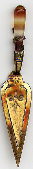 This bookmark is made in Scotland. It is a brass trowel with a Carnelian handle surrounded by a brass snake. The date is unknown.