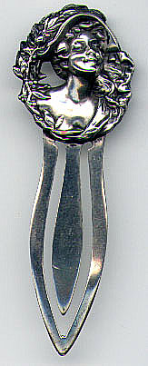 This bookmark was made in the US by an unknown manufacturer. It is only marked sterling on the back. The top of the mark is an art nouveau lady head wearing a hat surrounded by a wreath of leaves and flowers. The date is 1900 -1910.