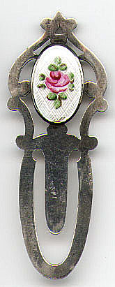 This bookmark was made in the US by Webster sometime between 1910 - 1930. It is marked Webster Sterling with the manufacturers hallmark. The shape of this bookmark has been used on a number of bookmarks with different tops. This one has an enamel picture of a rose. The other ones in this collection with this shape are #74 and #134.