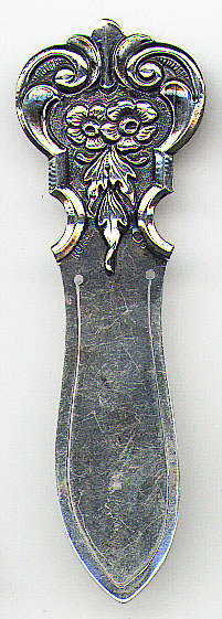 This bookmark was made in Norway and imported into Sweden. It is marked with the Swedish import marks and the letter S. It is also marked Norge. The top is an art nouveau with flowers. The date is 1910 - 1920.