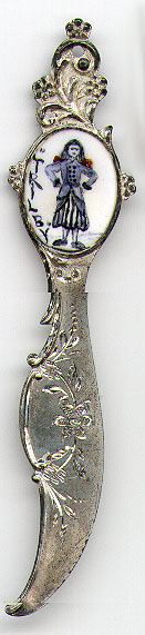 This bookmark was made in the US by an unknown manufacturer. It is marked only Sterling on the back of the small blade behind the top blade. The front has an enamel picture of woman, arms akimbo, and the name "Trilby". Date is 1900 - 1910.
