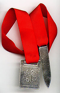 This bookmark was made in the US by Leonore Doskow between 1934 and 1950. It has two pieces each marked Leonore Doskow handmade sterling. The two pieces are connected by a red ribbon.
