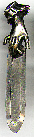 This bookmark was made in the US by an unknown manufacturer and sold in the 1888 catalog of the Horton, Gilmore, McWilliams & Company. It is silver plate over brass and shows a hand with crossed fingers on the top. 
