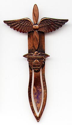 This bookmark was made in the US by an unknown manufacturer. made of copper and is unmarked. It is from the Army Air Corps and shows a propeller with wings and a shield with Washington DC on it. The date is 1940 - 1950.  