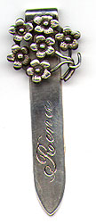  This bookmark was made in the US by an unknown manufacturer. It is only marked Sterling on the back of the blade. The top blade is a cluster of 5 pedal flowers. The bottom blade is inscribed Rena. The date is 1900 - 1910.  