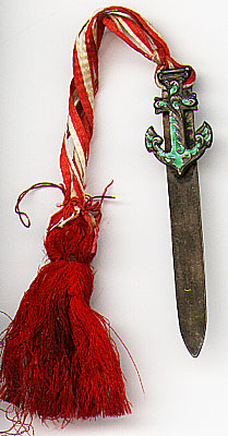 This bookmark was made in the US by an unknown manufacturer. It is marked E sterling on the back. The top blade is in the shape of an anchor with partial green enamel. It has a red and white ribbon and tassel. The date is 1900 - 1910.  
