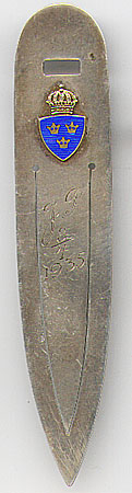 This bookmark was made in Sweden in 1932. It is marked CGH, other Swiss marks and the year mark F8. The top has a blue enamel shield with three crowns within and is topped by a more ornate crown. The middle blade is inscribed "J.P. 8/4 1935".