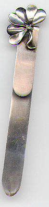 This bookmark was made in the US by Thomas F. Brogan of New York. It is marked with the makers hallmark which is a 5 pointed star and the word sterling. The top is a figural clover. The date is 1896 - 1930.