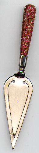  This bookmark was made in the US or Scotland. It is a masonic piece in the shape of a trowel with a goldstone handle. The date is sometime in the 1950s when goldstone was very popular.    