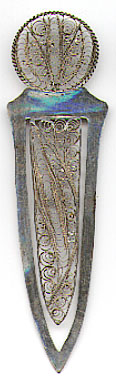  This bookmark was made in the US by an unknown manufacturer. It is unmarked but is probably silver. It has intricate filigree work on the top and on the inner blade. The date is 1900 - 1910.   